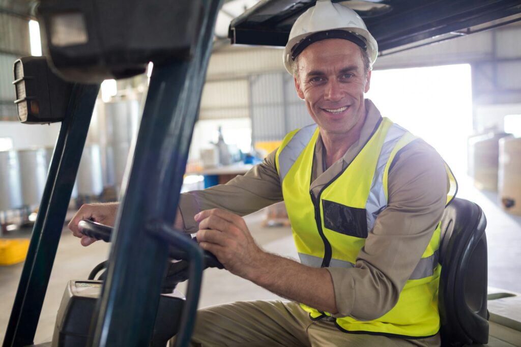 Portrait of happy worker driving forklift